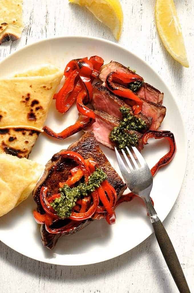 Steak with Pesto and chargrilled capsicum on a white plate, ready to be eaten.