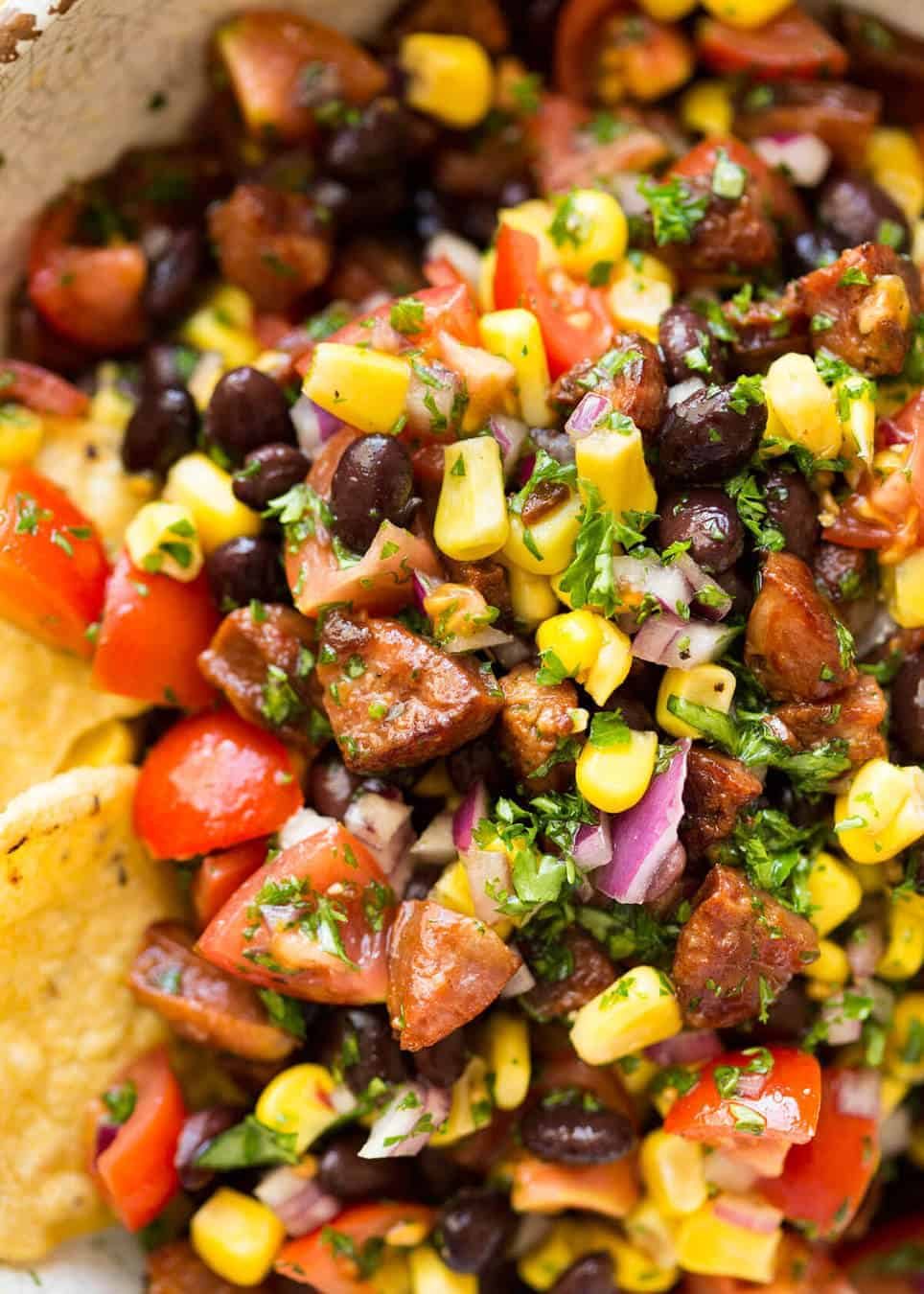Close up of Pig Out Salsa - a side made with golden browned cooked chorizo, corn, b lack beans, tomato and red onion.