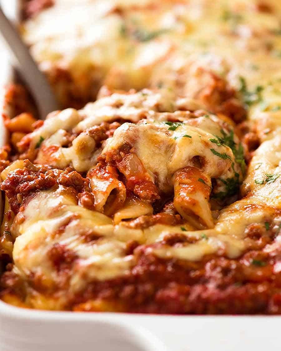 Scooping up Baked Ziti from baking dish